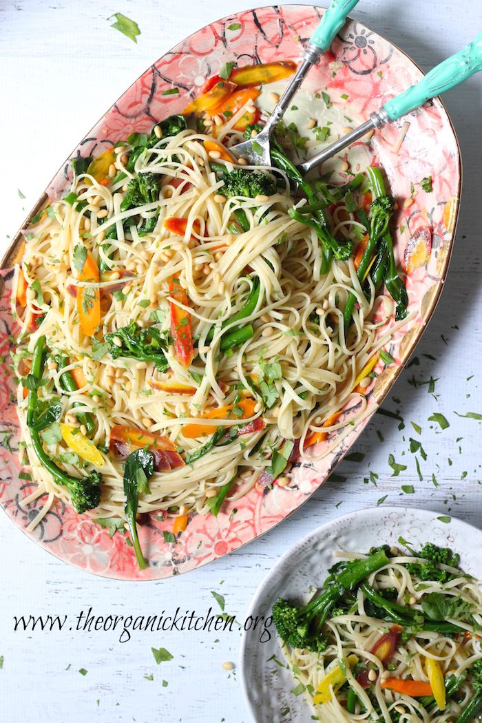 A platter of Linguini with Rainbow Carrots and Broccolini with turquoise serving utensils
