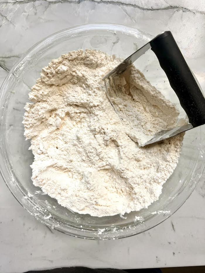 Dough in a glass bowl with a pastry cutter