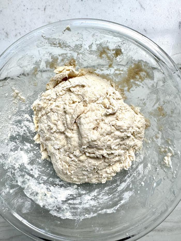 Biscuit dough in a glass bowl on a marble surface