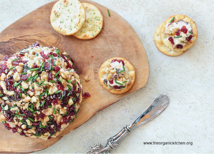 Homemade Cranberry Nut Cheese Ball on serving board set on marble surface