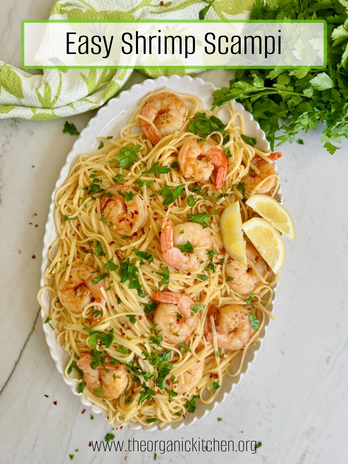 A while platter spilling over with Easy Shrimp Scampi, green dish towel and parsley in the background