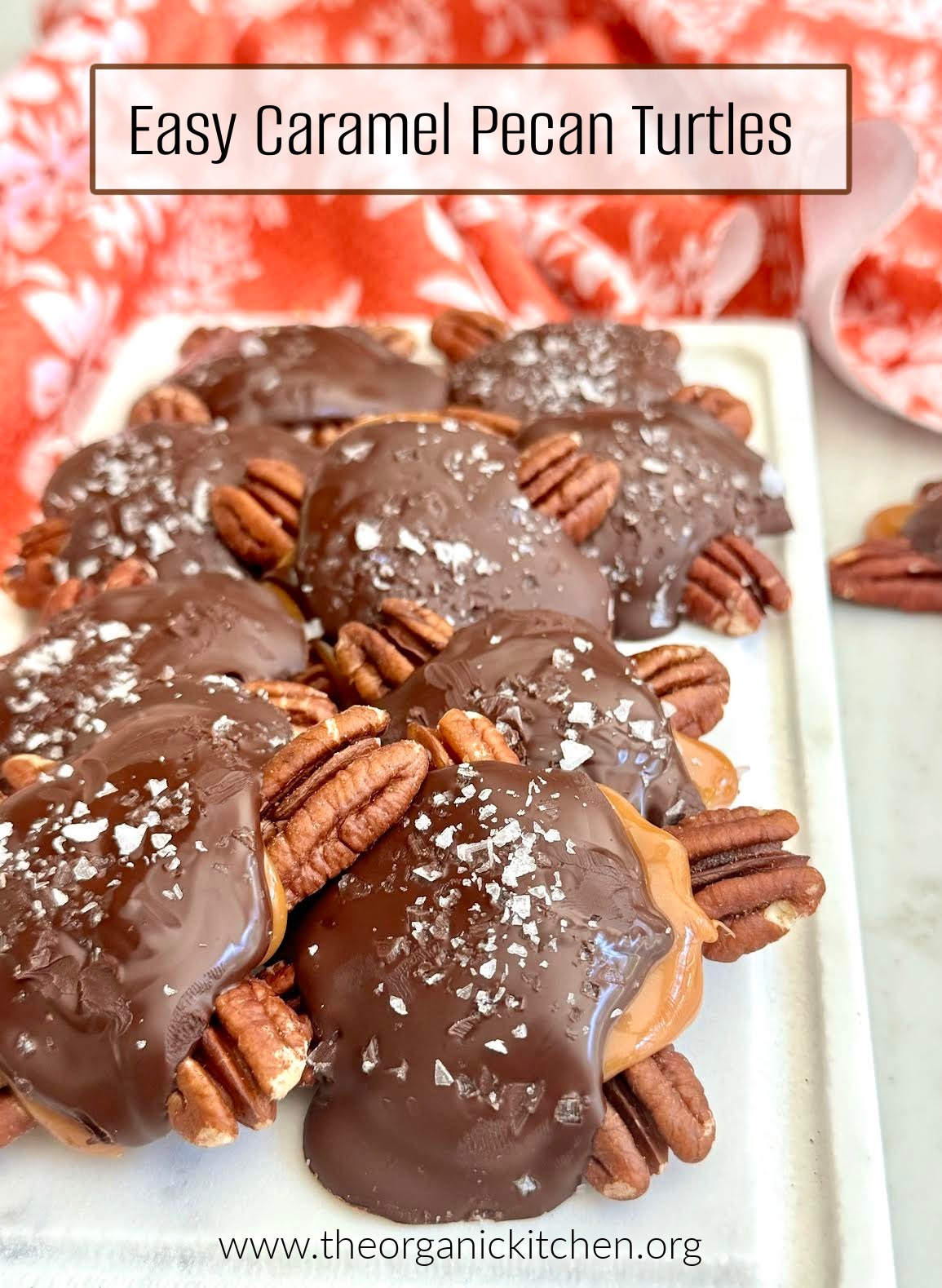 Easy Caramel Pecan Turtles sprinkled with sea salt on white plate with red dish towel in background