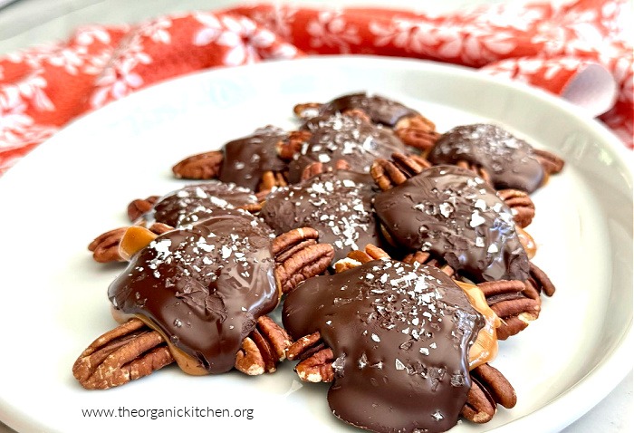 Easy Caramel Pecan Turtles on white plate with red dish towel in the background