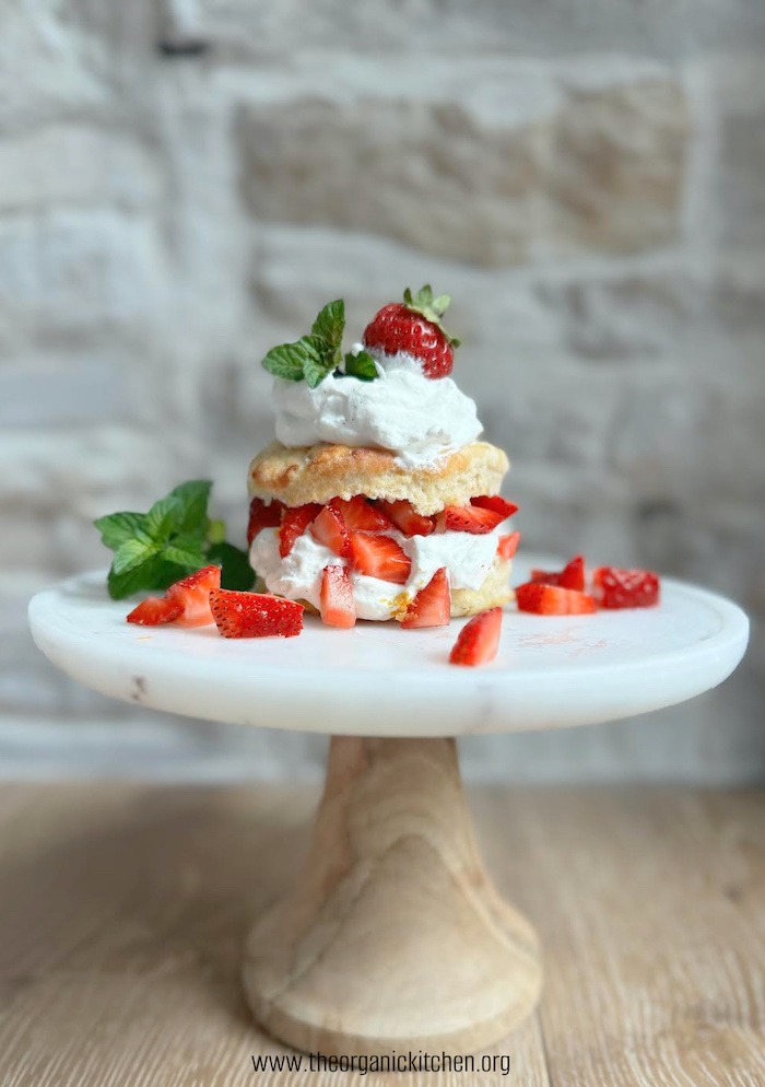 Old Fashioned Strawberry Shortcake with mint leaves on a cake plate in front of stone wall